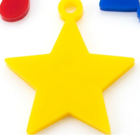 Colorful plastic charms including a star, heart, and clover on a white background