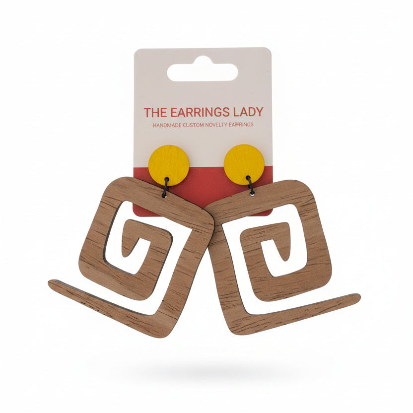 Wooden earrings on a card held by a hand with a pegboard background