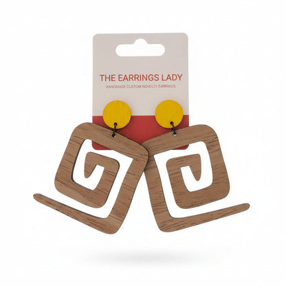 Wooden earrings on a card held by a hand with a pegboard background