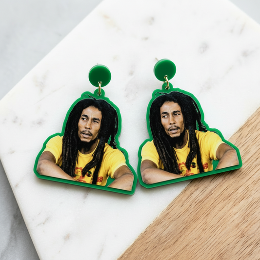 Earrings with a portrait of a person in a yellow shirt on a marble surface