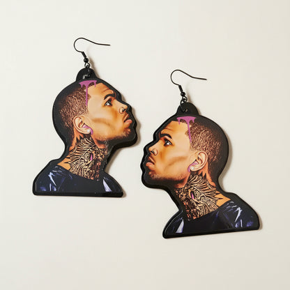 Earrings with a design of a chris brown's face and tattoos on a plain background
