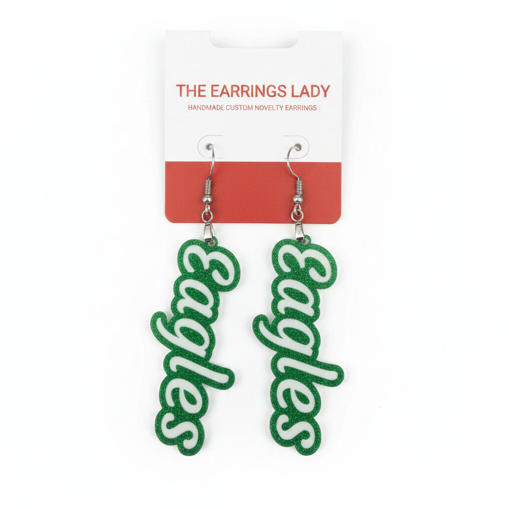 A pair of novelty dangle earrings shaped like the Philadelphia Eagles logo, hanging from a white and red display card labeled 'THE EARRINGS LADY'.