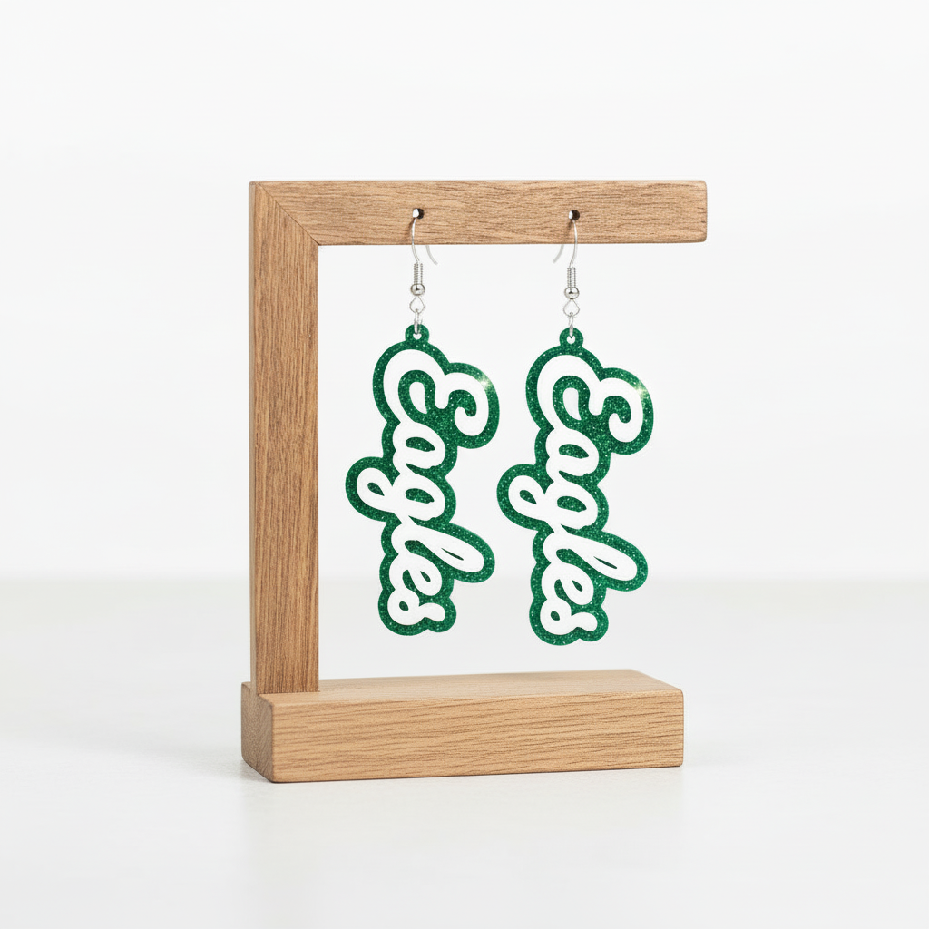Pair of earrings with 'Eagles' text on a wooden stand with a natural background