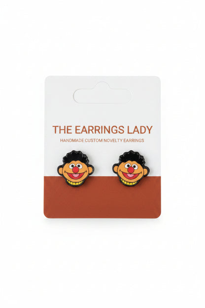 Pair of novelty earrings with a cartoon character design on a branded card.