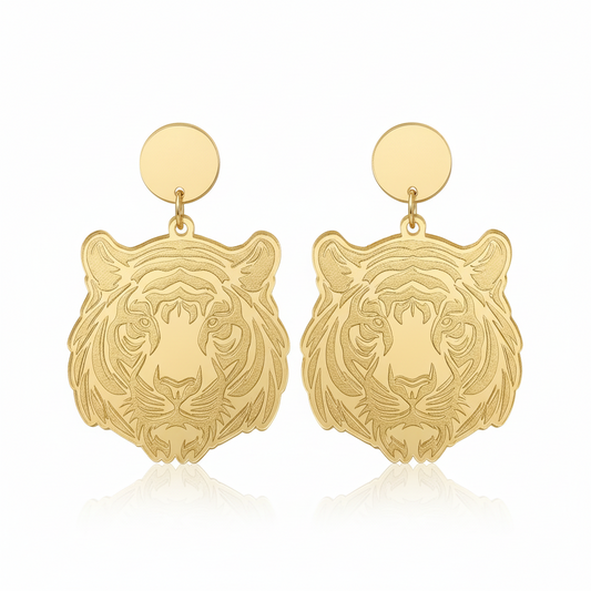 Gold tiger head earrings on a beige background