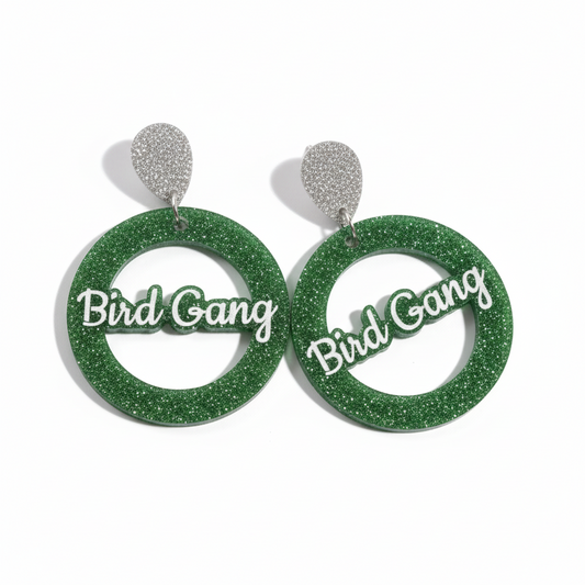 Green glittery earrings with 'Bird Gang' text on a white background