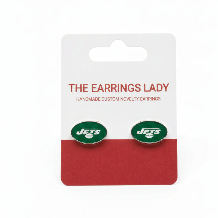 A pair of oval stud earrings with the New York Jets logo, presented on a white and red card backing labeled 'THE EARRINGS LADY', placed on a textured carpet background.