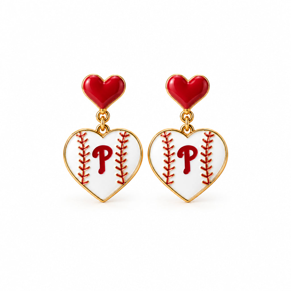 A pair of heart-shaped dangling earrings displayed on a white retail card. The earrings have a white face with red baseball-stitch details and a red heart at the top, with gold-tone connectors.