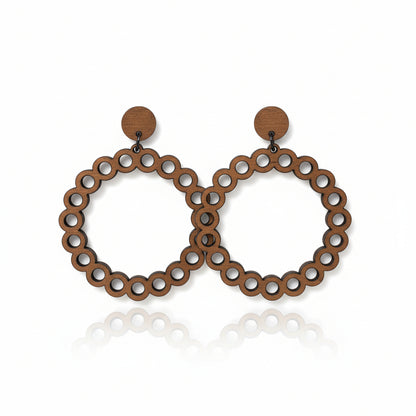 Hand holding a pair of hoop earrings with 'The Earrings Lady' packaging in an indoor setting.