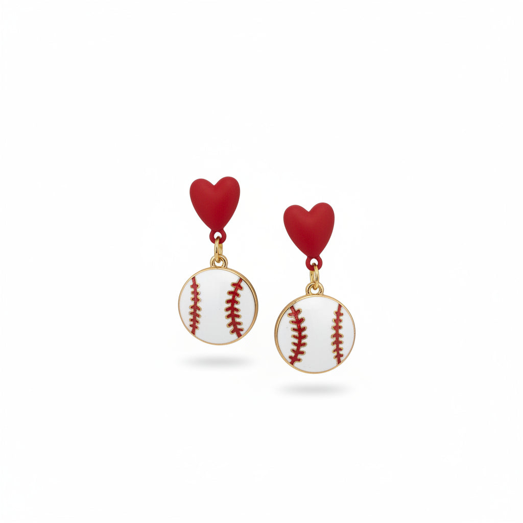 A hand holds a pair of handmade baseball-themed earrings on a white backing card from 'The Earrings Lady'. The earrings feature red heart studs and white baseball charms with red stitching.
