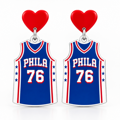 A pair of basketball jersey-shaped earrings or charms featuring the Philadelphia 76ers logo, with blue jerseys, red and white trim, the number 76, and a red heart at the top, shown on a gray background.