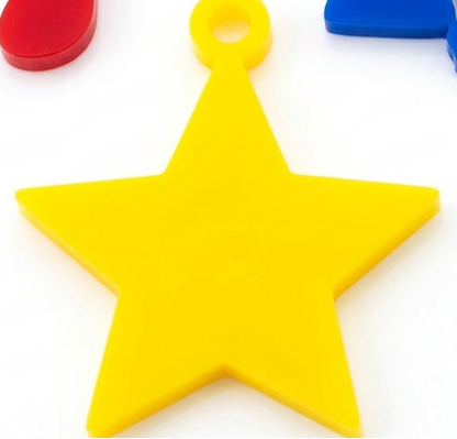 Colorful plastic charms including a star, heart, and clover on a white background
